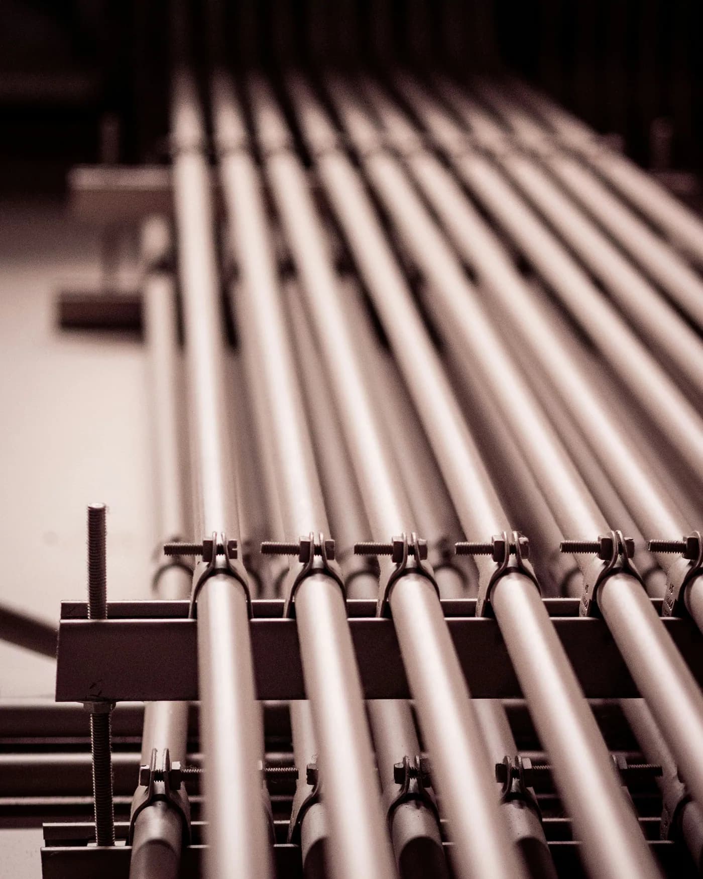 Rows of parallel steel conduit clamped to a support rack, running into the distance